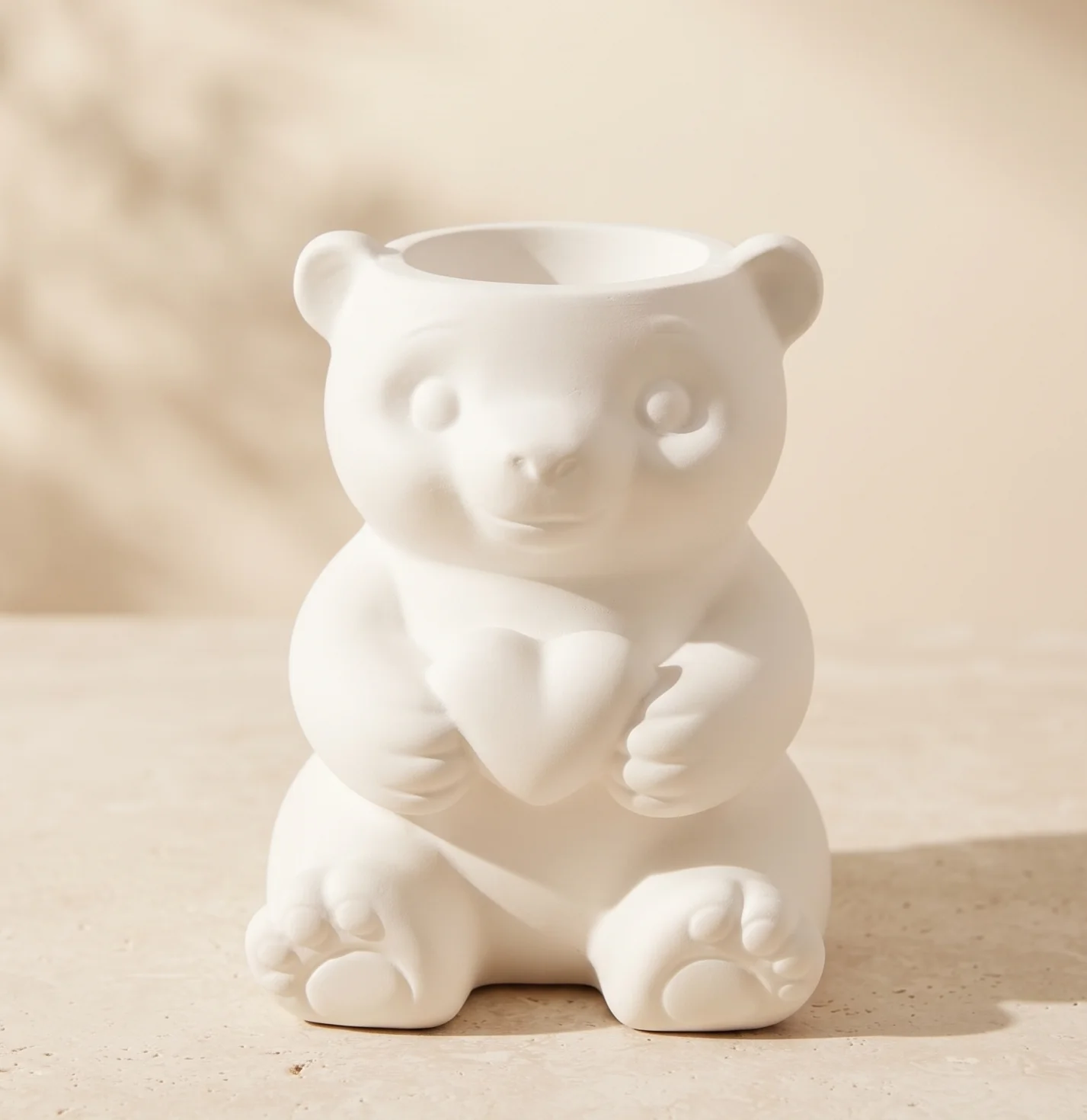 Portalápices decorativo de yeso blanco con diseño de osito abrazando un corazón de frente